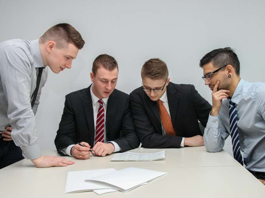 four men looking to the paper on table
